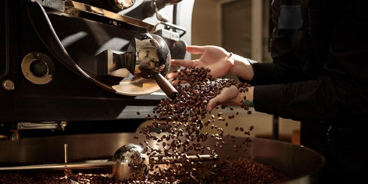 Person handling coffee beans during the roasting process